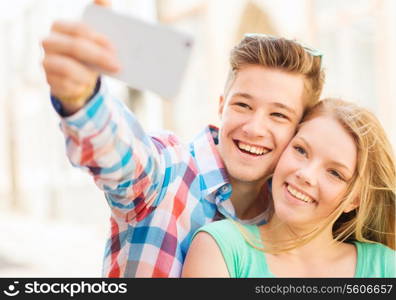 travel, vacation, technology and friendship concept - smiling couple with smartphone in city