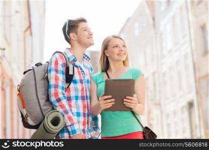 travel, vacation, technology and friendship concept - smiling couple with tablet pc and backpack in city