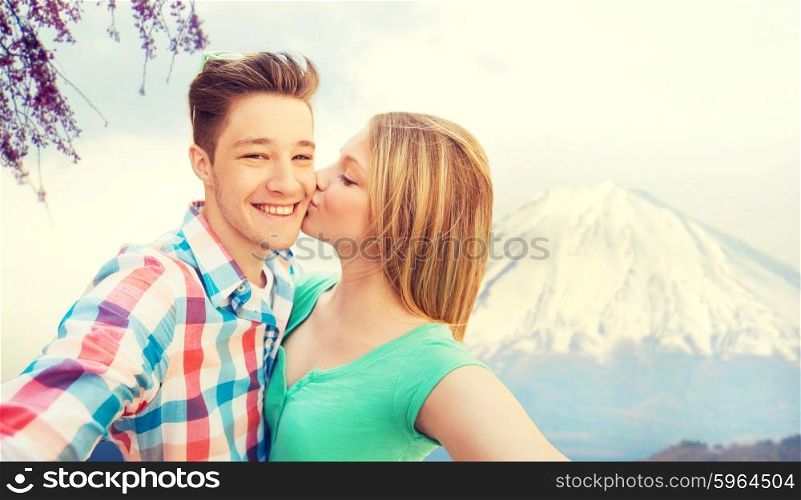 travel, vacation, technology, people and love concept - smiling couple taking selfie with camera or smartphone over japan mountains background