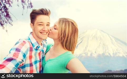 travel, vacation, technology, people and love concept - smiling couple taking selfie with camera or smartphone over japan mountains background