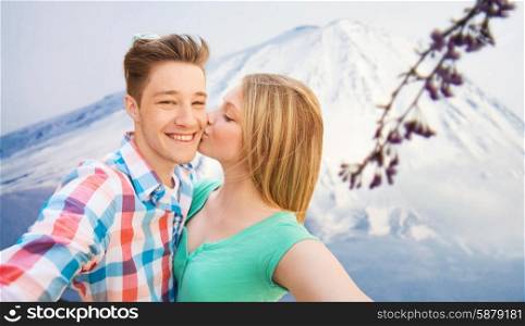 travel, vacation, technology, people and love concept - smiling couple with smartphone over japan mountains background
