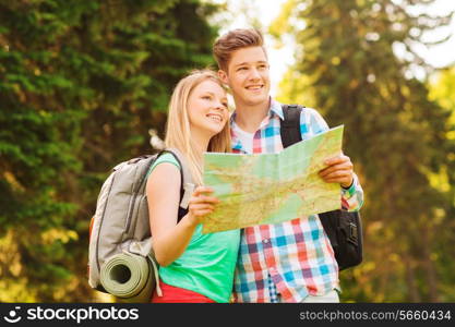 travel, vacation, tourism and friendship concept - smiling couple with map and backpack in forest