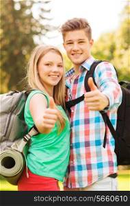travel, vacation, tourism, gesture and friendship concept - smiling couple with backpacks showing thumbs up in nature