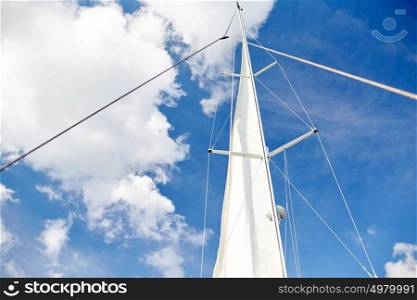 travel, yachting and sailing concept - white sail on mast of boat over blue sky. white sail on mast of boat over blue sky