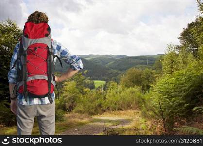 Traveler absorbing the view of the Belgium Ardennes, as he clears the woods on top of a hill