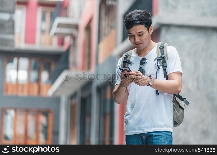 Traveler Asian man direction on location map in Beijing, China, backpacker male using mobile phone looking on map find landmark while holiday trip. Lifestyle men travel in city concept