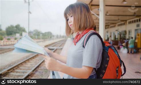 Traveler Asian woman direction and looking on location map while spending holiday trip and waiting train at train station, Young female tourist backpacker enjoy journey. Lifestyle women travel concept