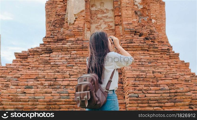 Traveler Asian woman using camera for take a picture while spending holiday trip at Ayutthaya, Thailand, Japanese female tourist enjoy her journey at amazing landmark in traditional city.