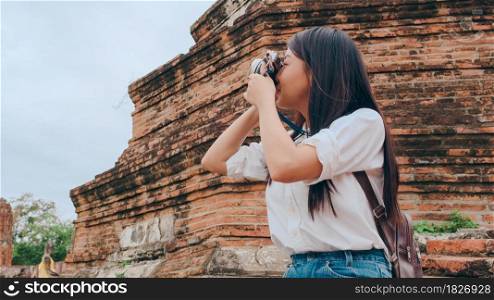 Traveler Asian woman using camera for take a picture while spending holiday trip at Ayutthaya, Thailand, Japanese female tourist enjoy her journey at amazing landmark in traditional city.
