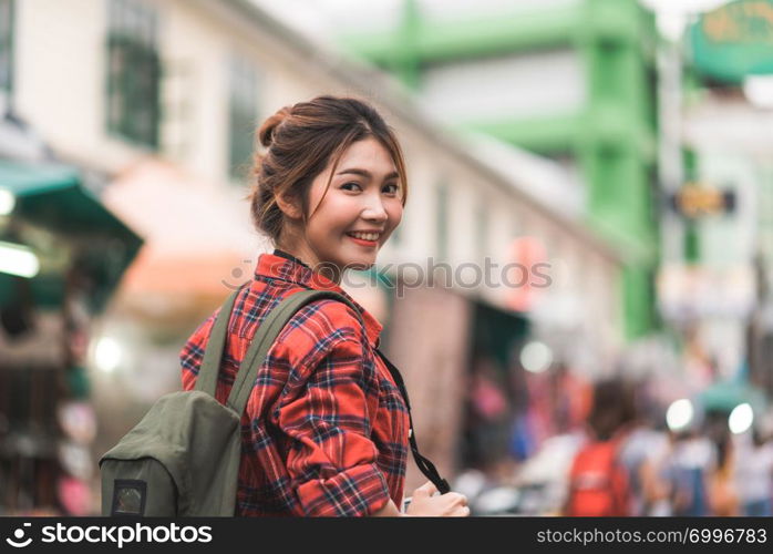 Traveler backpacker asian woman travel in Khao San road at Bangkok, Thailand. Happy young female spending holiday trip at amazing landmark and enjoy her journey in traditional city.