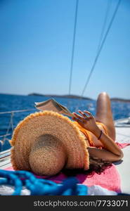 Traveler Girl with Pleasure Reading Book and Tanning on the Sailboat. Enjoying Active Summer Holidays. Traveling to Greece.. Reading Book on Sailboat