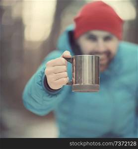 traveler in a winter forest drinks a hot drink and holds a cup