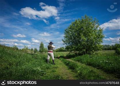 traveler in old clothes with a knapsack on an abandoned country road