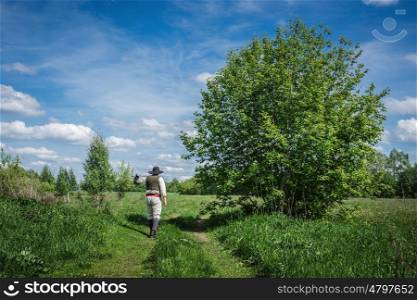 traveler in old clothes with a knapsack on an abandoned country road
