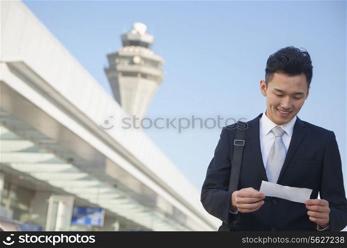 Traveler looking at ticket at airport