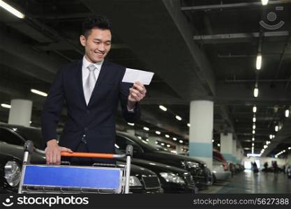 Traveler looking at ticket in airport parking lot