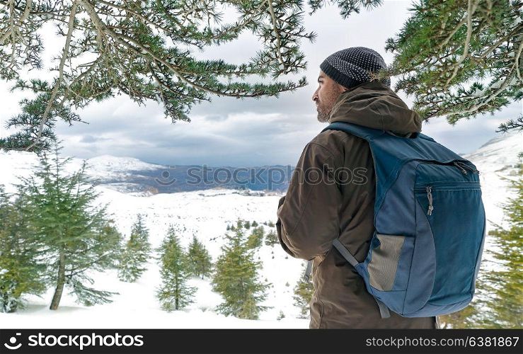 Traveler man in the snowy mountains enjoying beautiful view of fir trees covered with snow, eco tourism, active winter traveling