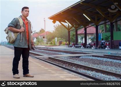 Traveler man waiting with backpack in train station. Travel concept.