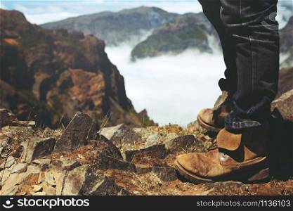 Traveler resting man hipster hiking boots Standing on a high mountain peak having enjoying wonderful breathtaking the forest mountain rocks view. Freedom travel concept. hiking shoes and man legs.