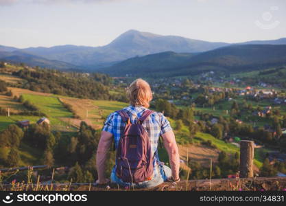 Traveler sitting on wooden fence at the mountain top