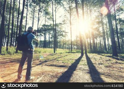 Traveler taking a photo in forest with sunlight in the morning. Hope light, travel and vacation concept.