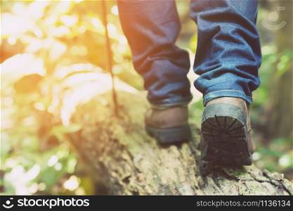 traveler tourist Close up leg of young hipster man one person hiker shoe boots hiking. tourist hikers in adventure forest step trail walking stepping going up the stairs with sunshine. travel concept