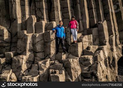Traveler travel to unique volcanic rock formation on Iceland black sand beach located near the village of Vik i myrdalin South Iceland. Hexagonal columnar rocks attract tourist who visit Iceland.