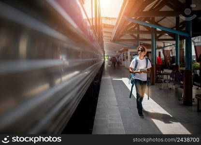 Traveler waits train at train station for travel in summer. Travel concept.