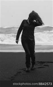 Traveler walking along on Reynisfjara beach monochrome scenic photography. Picture of person with rough sea on background. High quality wallpaper. Photo concept for ads, travel blog, magazine, article. Traveler walking along on Reynisfjara beach monochrome scenic photography