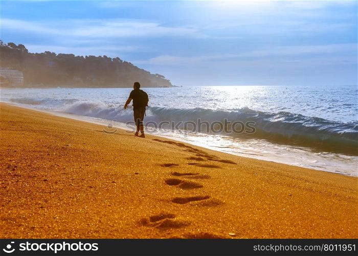 Traveler walking along the sandy beach at popular holiday resort Lloret de Mar on Costa Brava in the morning , Catalunya, Spain