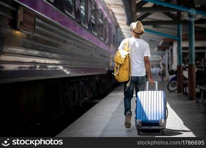 Traveler walking and waits train at train station for travel in summer. Travel concept.