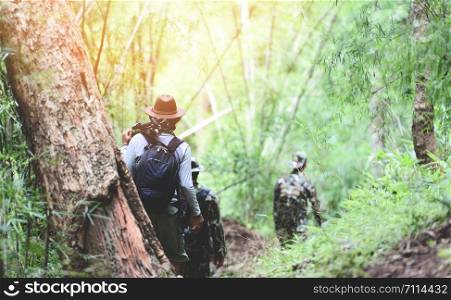 traveler walking in the bamboo forest / Men hikers mountain group of friends walking with backpacks and photographic equipment adventure travel tourism sports activity concept