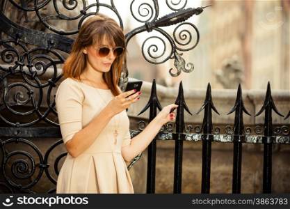 Traveler woman fashion girl with smart phone outdoors in european city, old town Gdansk Neptune fountain in the background, Poland Europe