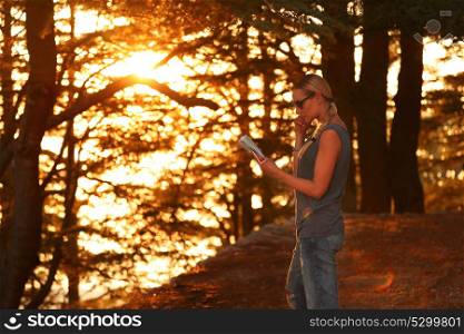 Traveler woman in the forest enjoying sunset, pretty girl standing in the woods with map in hand and searching right dirrection, active summer adventure