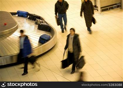 Travelers collecting luggage from airport baggage carousel.