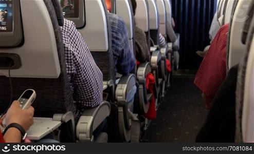 Travelers seated along the aisle of an airplane