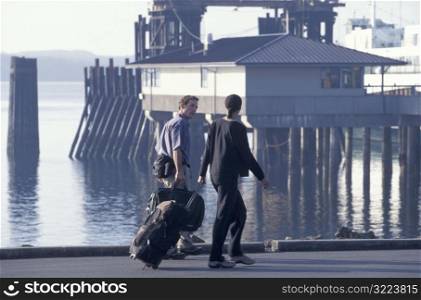 Travelers Walking With Suitcases Along The Pier