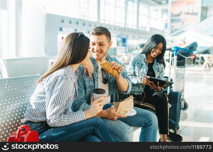 Travelers with luggage waiting for delayed departure in airport. Passengers with baggage looking forward to the flight in air terminal, holiday journey, summer air trip, travel on vacation. Travelers waiting for delayed departure in airport