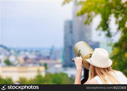 Traveling, adventure, vacation concept. Woman tourist wearing sun hat looking through telescope into the distance. Woman tourist with sun hat looking through telescope
