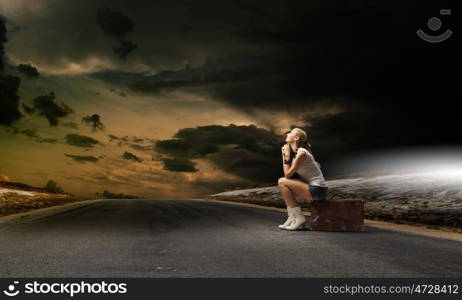 Traveling concept. Young girl traveler in shorts sitting on suitcase