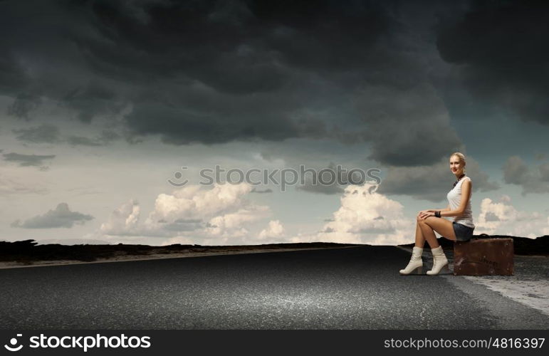 Traveling concept. Young girl traveler in shorts sitting on suitcase