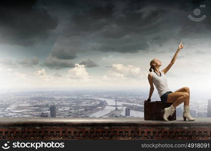 Traveling concept. Young girl traveler in shorts sitting on suitcase