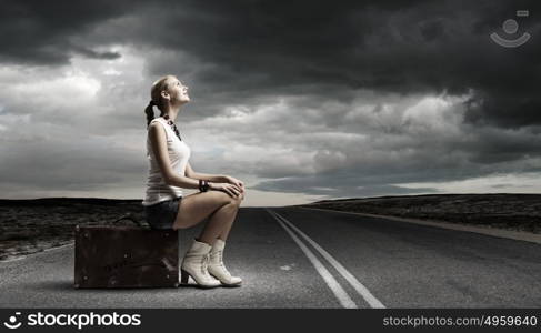 Traveling concept. Young girl traveler in shorts sitting on suitcase