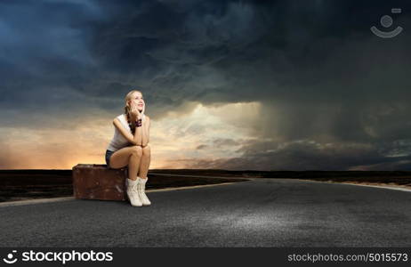 Traveling concept. Young girl traveler in shorts sitting on suitcase