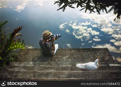 traveling man taking a photograph at old pier against beautiful blue sky reflection on water floor