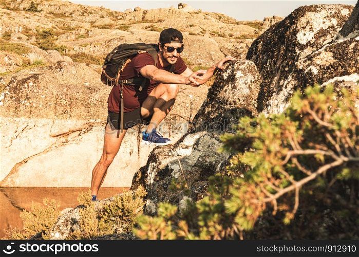 Traveling Man tourist with backpack climbing in mountains landscape active healthy lifestyle adventure vacations on rocky mountain.