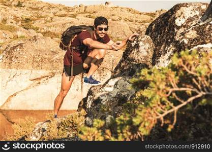 Traveling Man tourist with backpack climbing in mountains landscape active healthy lifestyle adventure vacations on rocky mountain.