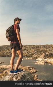 Traveling Man tourist with backpack hiking in mountains landscape active healthy lifestyle adventure vacations on rocky mountain.