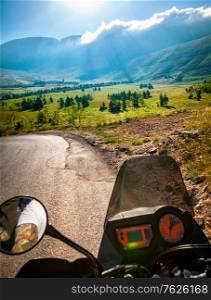 Traveling on the motorbike, active sportive people riding on the motorcycle along mountainous road, enjoying summer vacation among wild nature, freedom and tourism concept