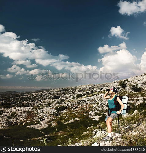 Traveling teen girl with backpack hiking in the mountains, healthy woman tourist looking at landscape view in binocular, sporty female enjoying summer nature outdoor, active people lifestyle